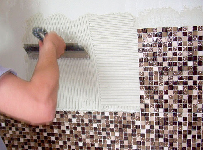 Нанесение плиточного клея на стену в ванной